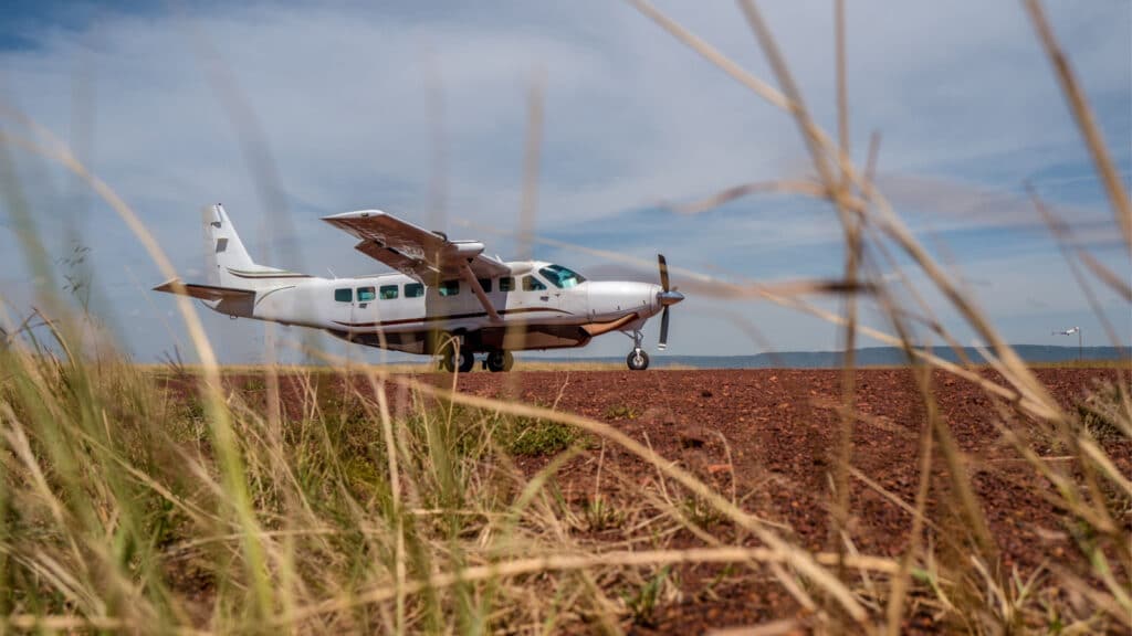 A small plane parked on a dirt field.