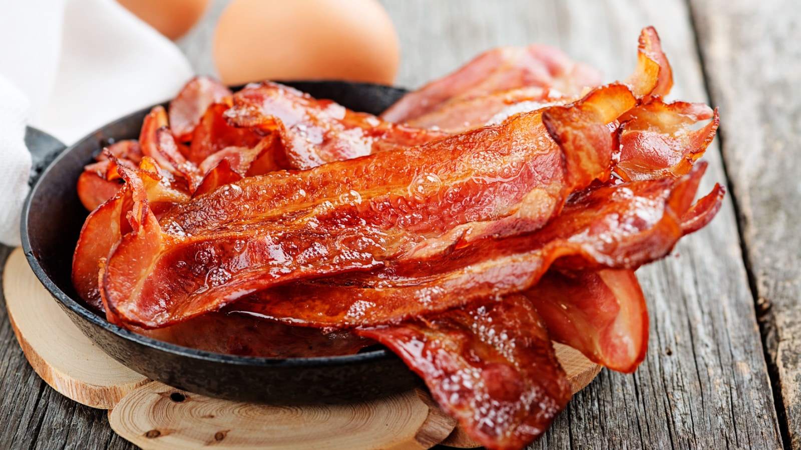 Hot fried bacon pieces in a cast iron skillet.top view