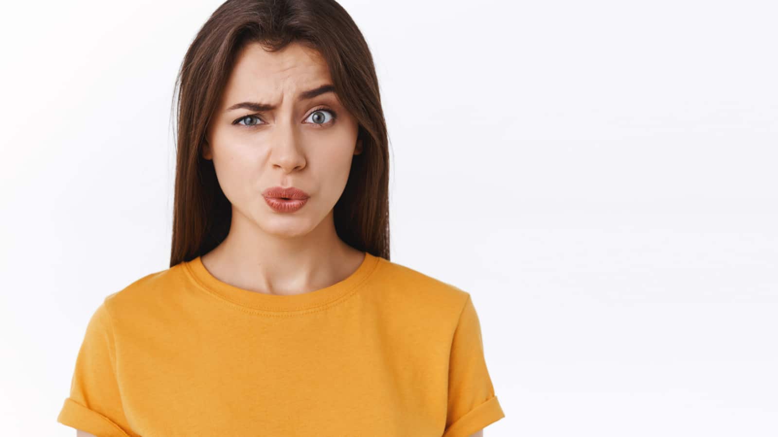 Ouch it probably hurts. Pity good-looking modern brunette woman in yellow t-shirt cringe and grimace as seeing someone got punched in face, folding lips and look uneasy camera, white background