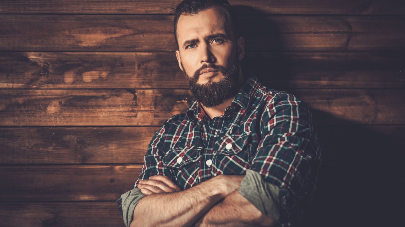 Handsome man wearing checkered shirt in wooden rural house interior