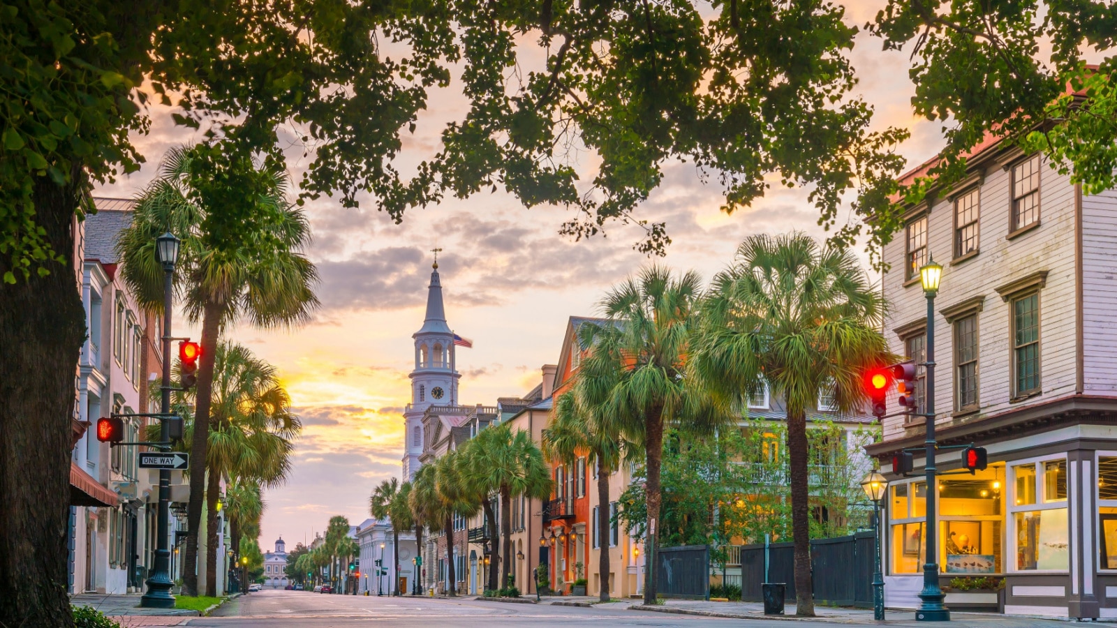 Historical downtown area of Charleston, South Carolina, USA at twilight. The emptying street is lined with trees and charming buildings.