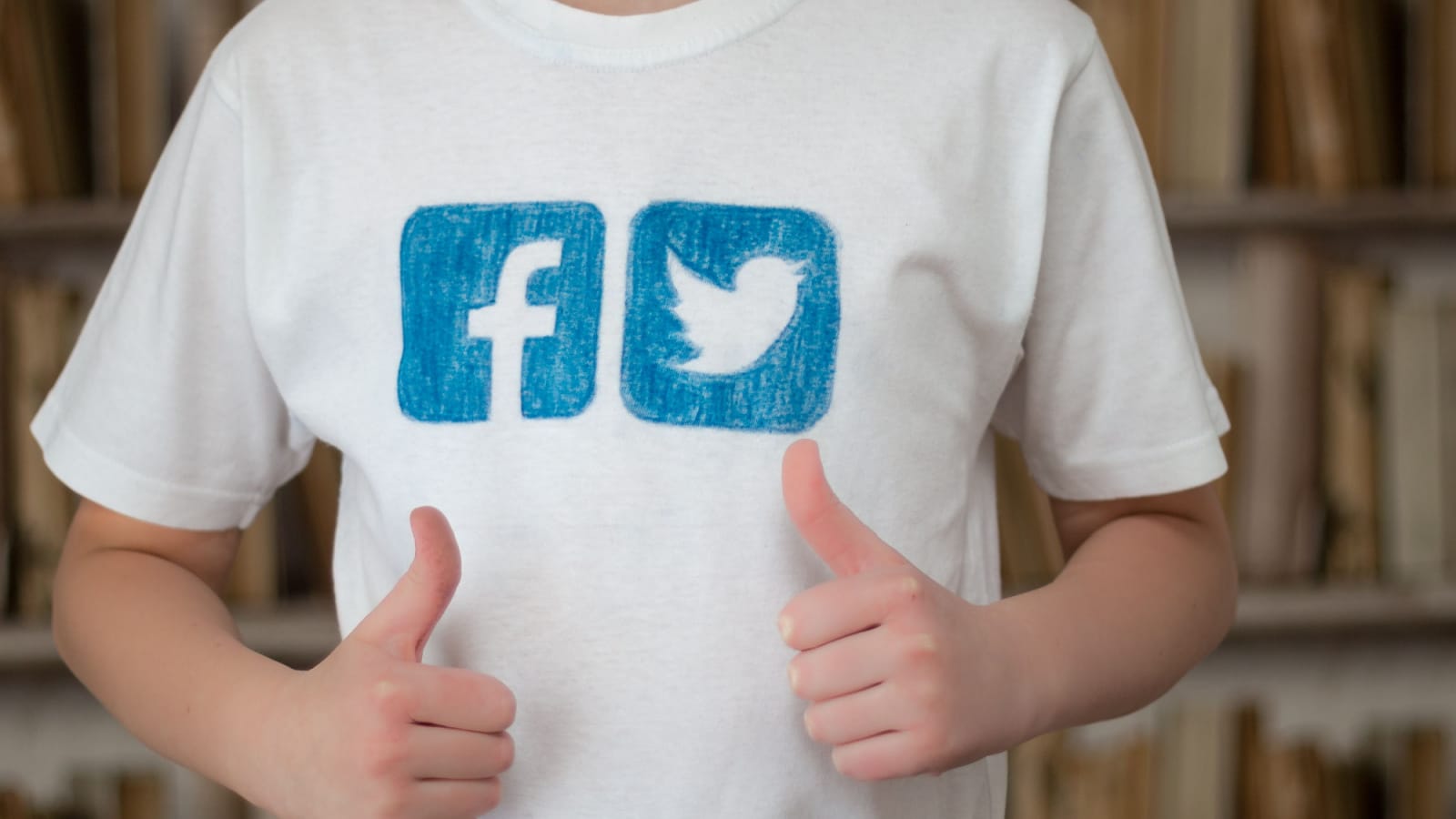 Minsk, Belarus - January 24, 2017: Boy teenager in a white T-shirt, with painted logos of popular social networks Facebook and Twitter, shows with his hand Like.