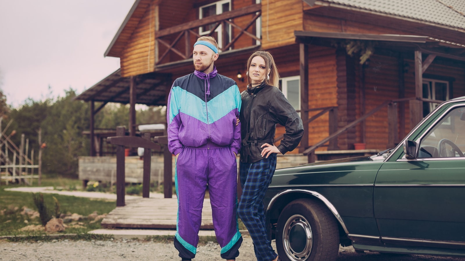 Guy and girl in clothes of the nineties, next to the old car