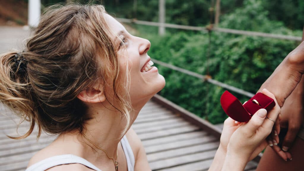 Woman proposing to her happy girlfriend outdoors love and marriage concept