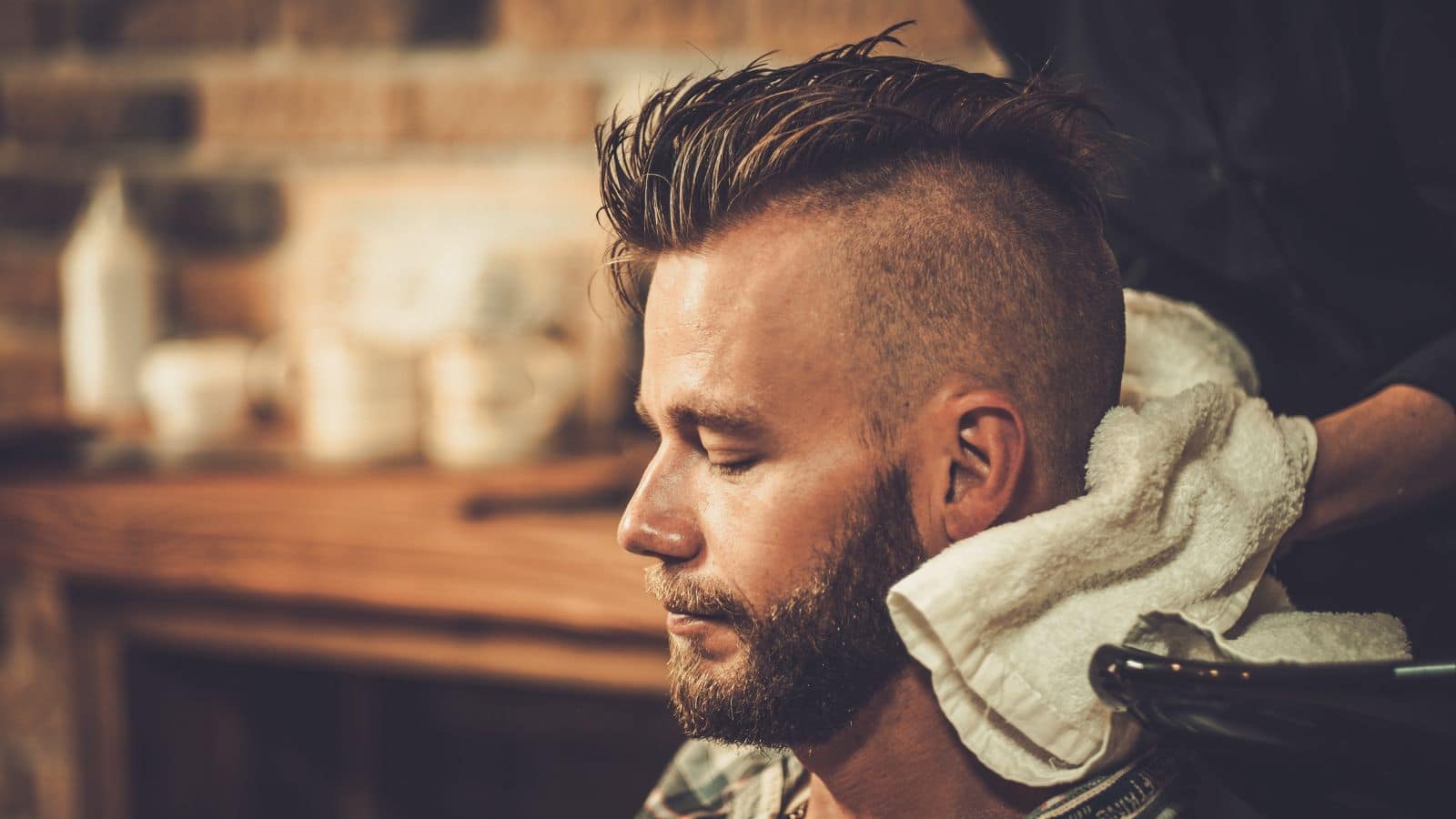 Hairstylist washing client's hair in barber shop