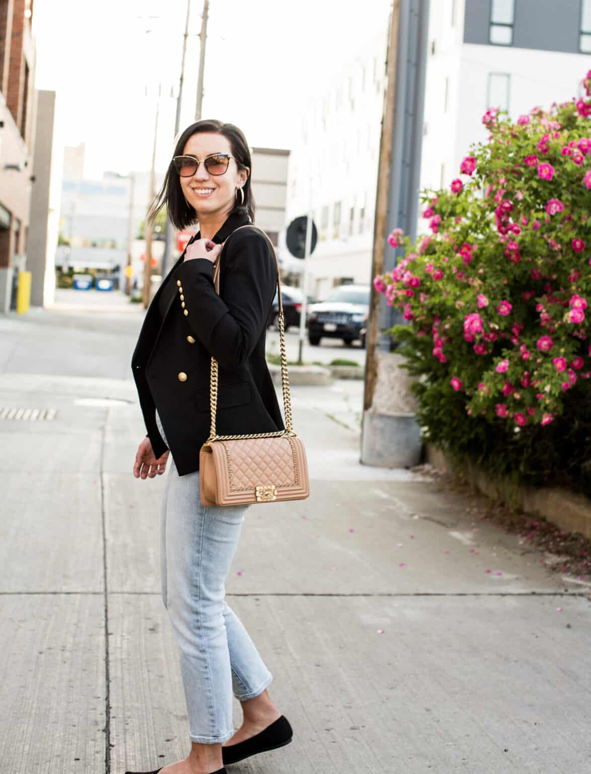 Lindsey of Have Clothes, Will Travel showing a pink Chanel boy bag paired with a black blazer and jeans