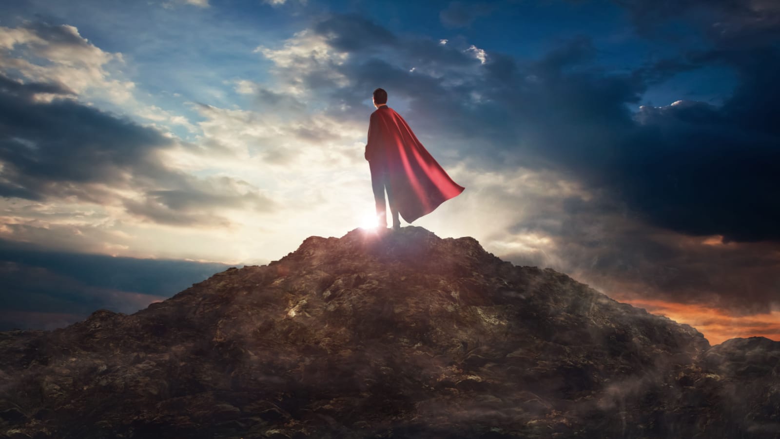 Businessman in a suit and cape hero on top of a mountain,Business Success concept.