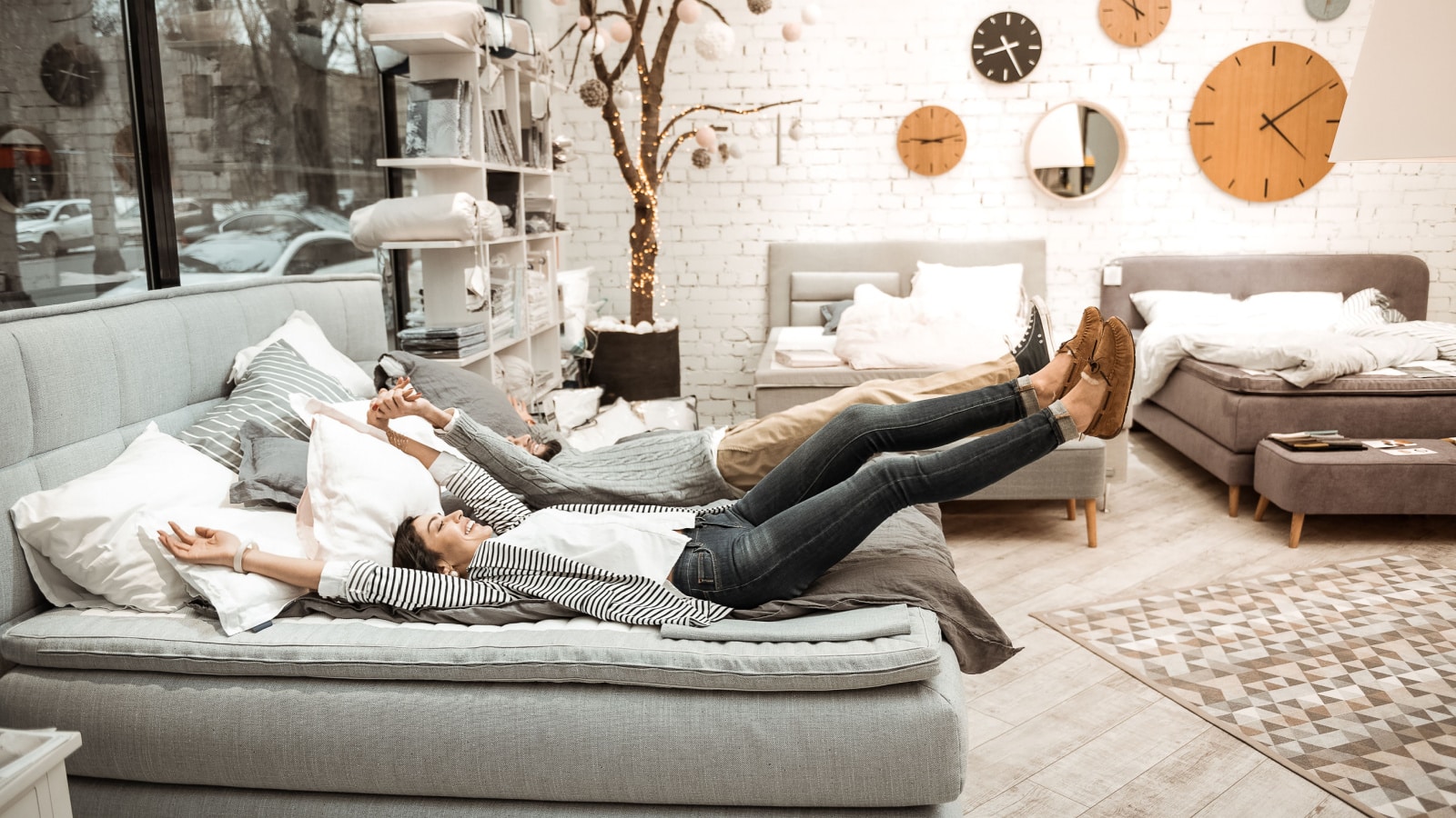 Being interested. Childish beaming couple fooling around while checking quality of bed presented in showroom