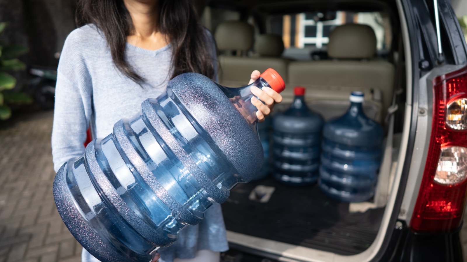 woman put a gallon of water in the car trunk at home. wanted to purchase the refill or by the new one