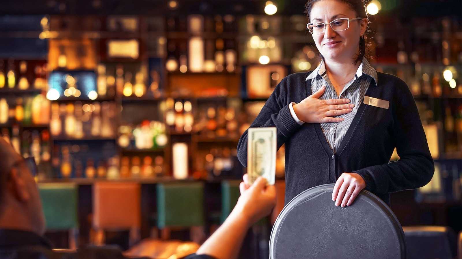 Waitress takes the tip. The waiter female receives a tip from the client at the hotel bar. The concept of service