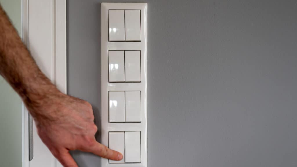 Row of eight light switches, while a finger switches on one light switch.