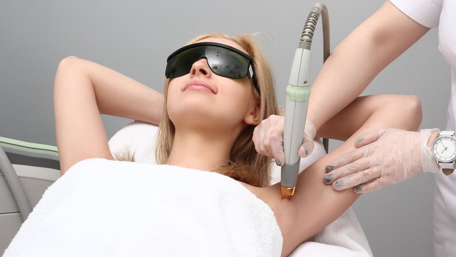 Blonde woman having underarm Laser hair removal epilation. Laser treatment in cosmetic salon