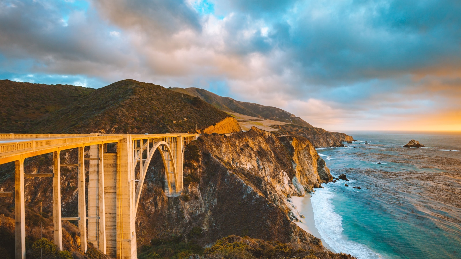 Scenic panoramic view of historic Bixby Creek Bridge along world famous Highway 1 in beautiful golden evening light at sunset with dramatic cloudscape in summer, Monterey County, California, USA