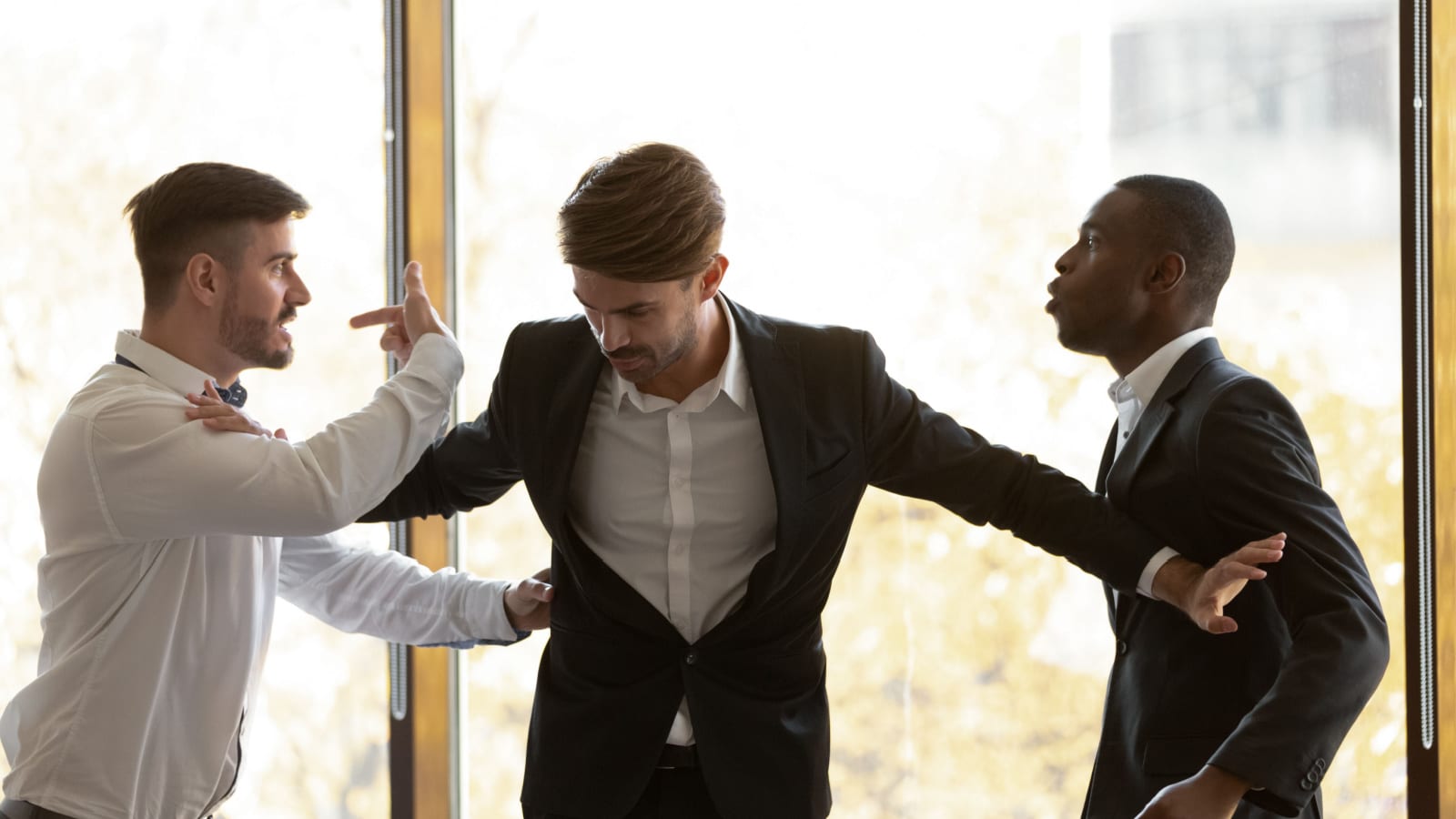 Male colleague set apart angry diverse business men coworkers argue fighting at corporate office meeting, mad employees quarreling shouting having conflict at work, racial hatred harassment concept