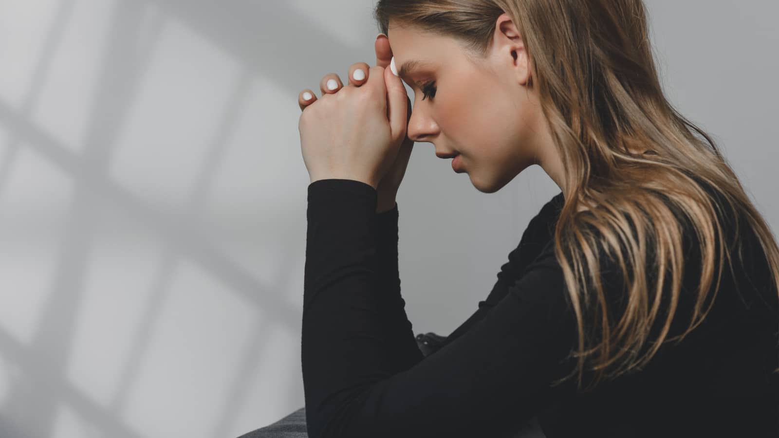 Portrait of a young beautiful long-haired girl who is upset crying, or praying.