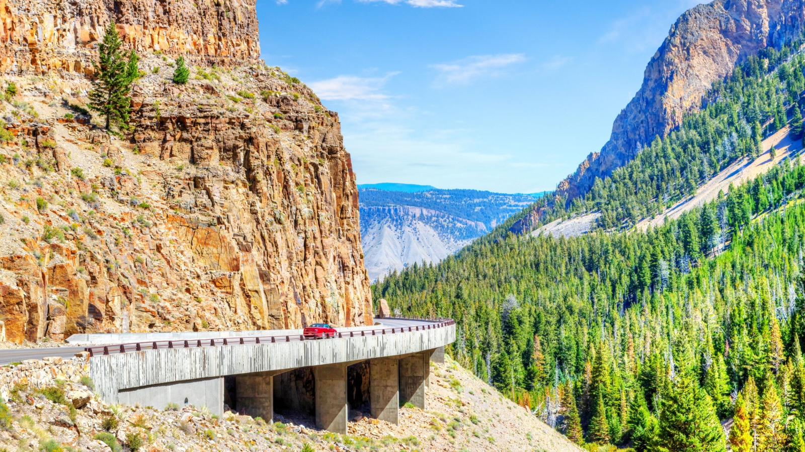 Red car on Grand Loop Road through Golden Gate Canyon at Kingman Pass in the northwestern region of Yellowstone National Park, Wyoming, USA.