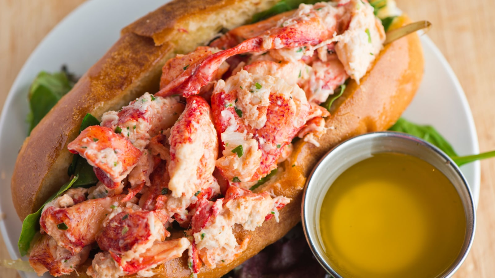 Lobster roll. Classic New England seafood sandwich. Lobster with lemon juice, mayo, butter, celery, scallions, dill, salt, pepper on a toasted hot dog bun. Served with Potato chips or French fries.