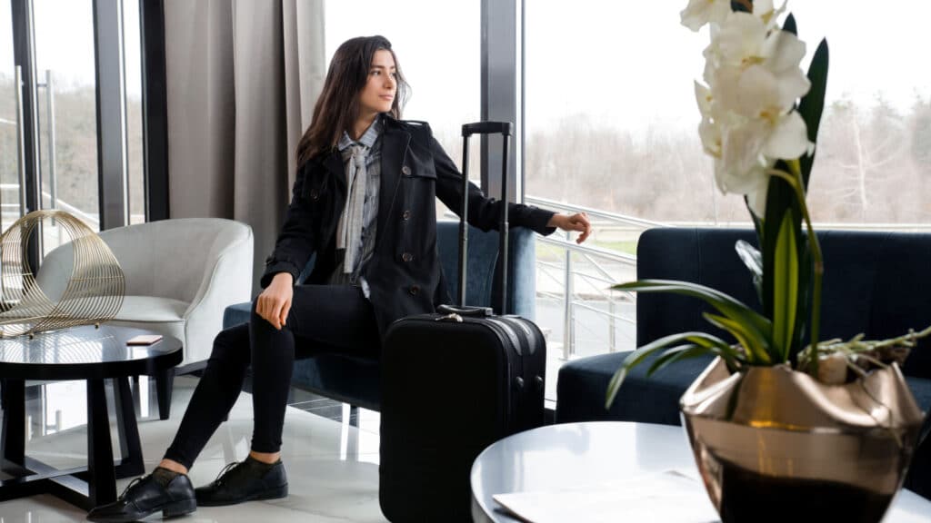 Woman sitting with suitcase in hotel lobby or in an airport lounge