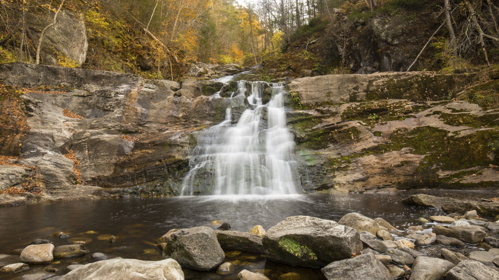 Blurred long exposure of the main waterfall at Kent Falls State Park in Kent, Connecticut, with fall foliage on the banks of Falls Brook.