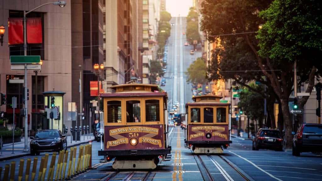 Classic view of historic traditional Cable Cars riding on famous California Street in morning light at sunrise with retro vintage style cross processing filter effect, San Francisco, California, USA