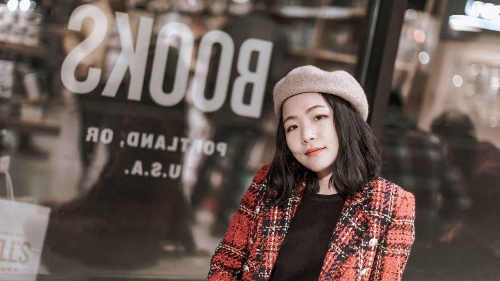 Portrait of young stylish hipster woman visiting old books store in Portland downtown, winter season