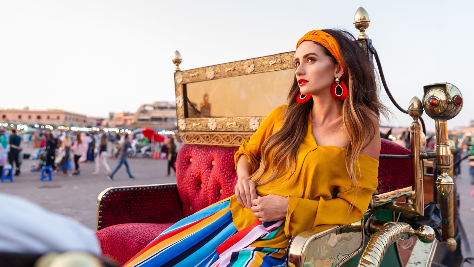 A beautiful girl is sitting in a carriage on the Djemaa el-Fna square. Marrakech, Morocco