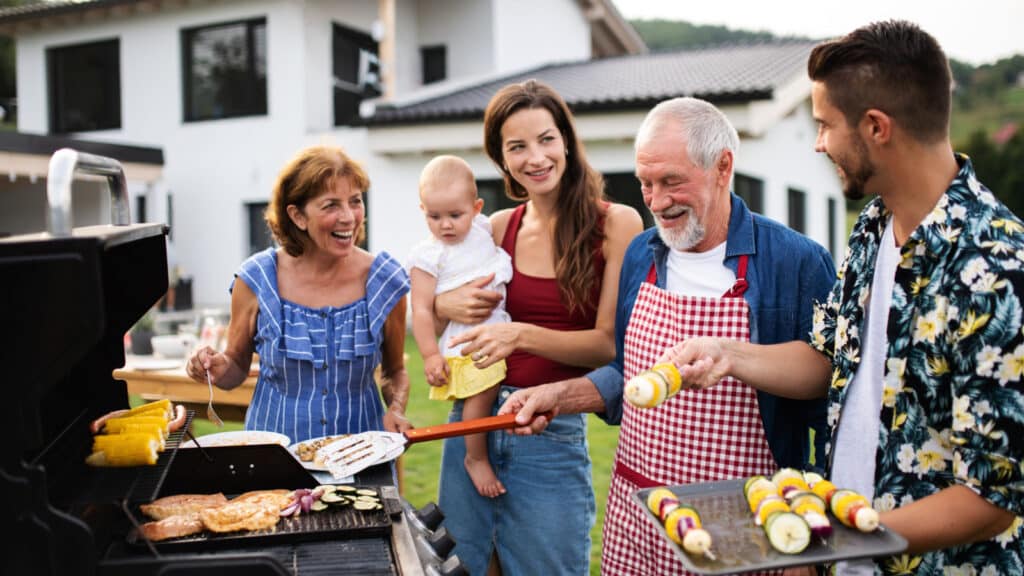 Portrait of multigeneration family outdoors on garden barbecue, grilling.