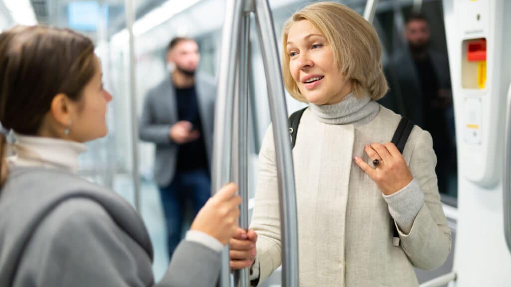 Two women passengers talking in subway car on way to work