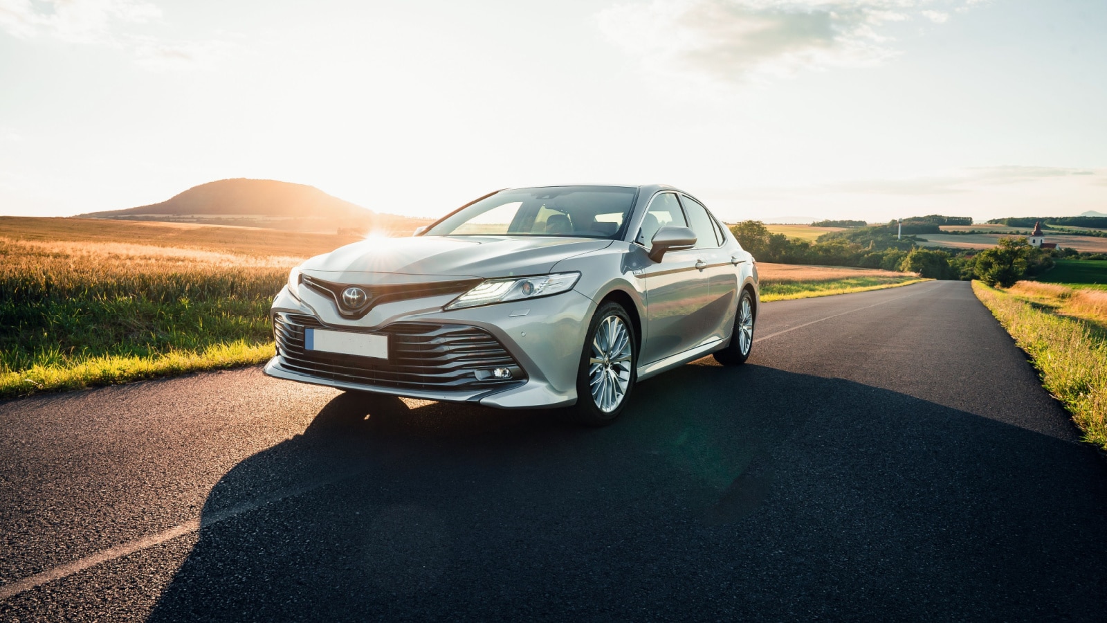 Prague, Czechia, 07-10-2020: Brand new Toyota Camry hybrid 2020 is driven at empty countryside asphalt road at sunset. Car in the ride.