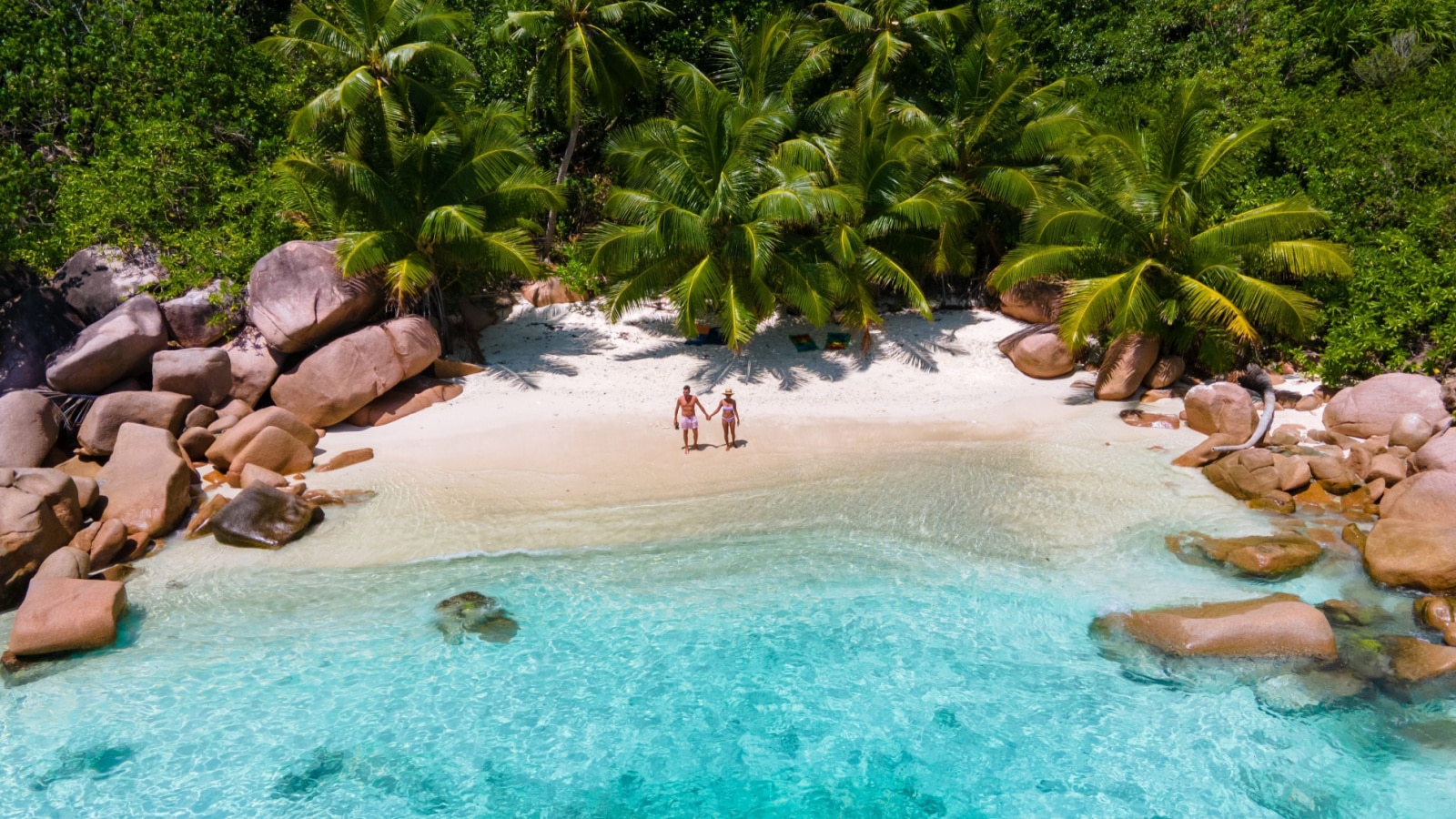 Anse Lazio Praslin Seychelles, a young couple of men and women on a tropical beach during a luxury vacation in Seychelles. Tropical beach Anse Lazio Praslin Seychelles