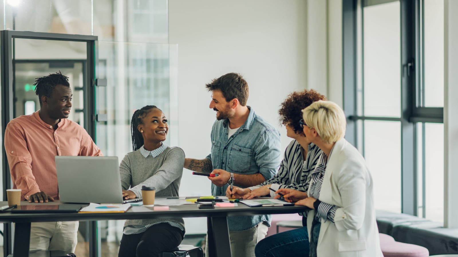 Startup multiracial business team on a meeting in a modern bright office interior. Woman team leader present project to her diverse colleagues.