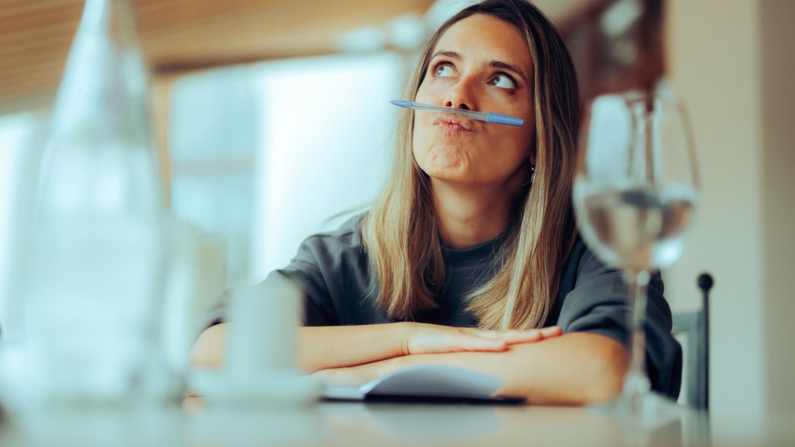 Funny Girl Balancing Pen on her Lips Procrastinating Writing. Uninspired writer going through a creative bloc trying to make fun of it