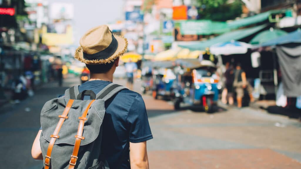 Young Asian traveling backpacker in Khaosan Road outdoor market in Bangkok, Thailand