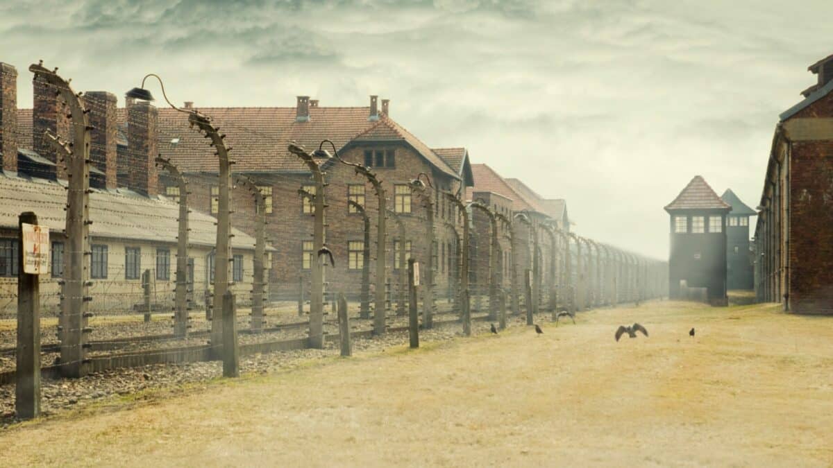 AUSCHWITZ, POLAND - March 30 2012 Holocaust Memorial Museum. Barbed wire around a concentration camp with crows and shed guard in the background