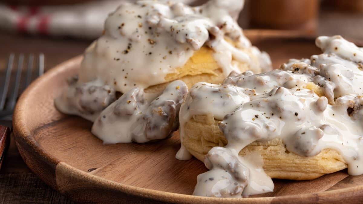 Closeup of biscuits and creamy sausage gravy on a wooden plate