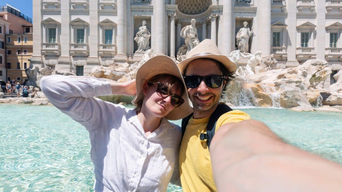 Tourist couple on travel taking selfie photo by Trevi Fountain in Rome, Italy. Happy young romantic couple traveling in Europe taking self-portrait with smartphone camera. Man and woman happy together