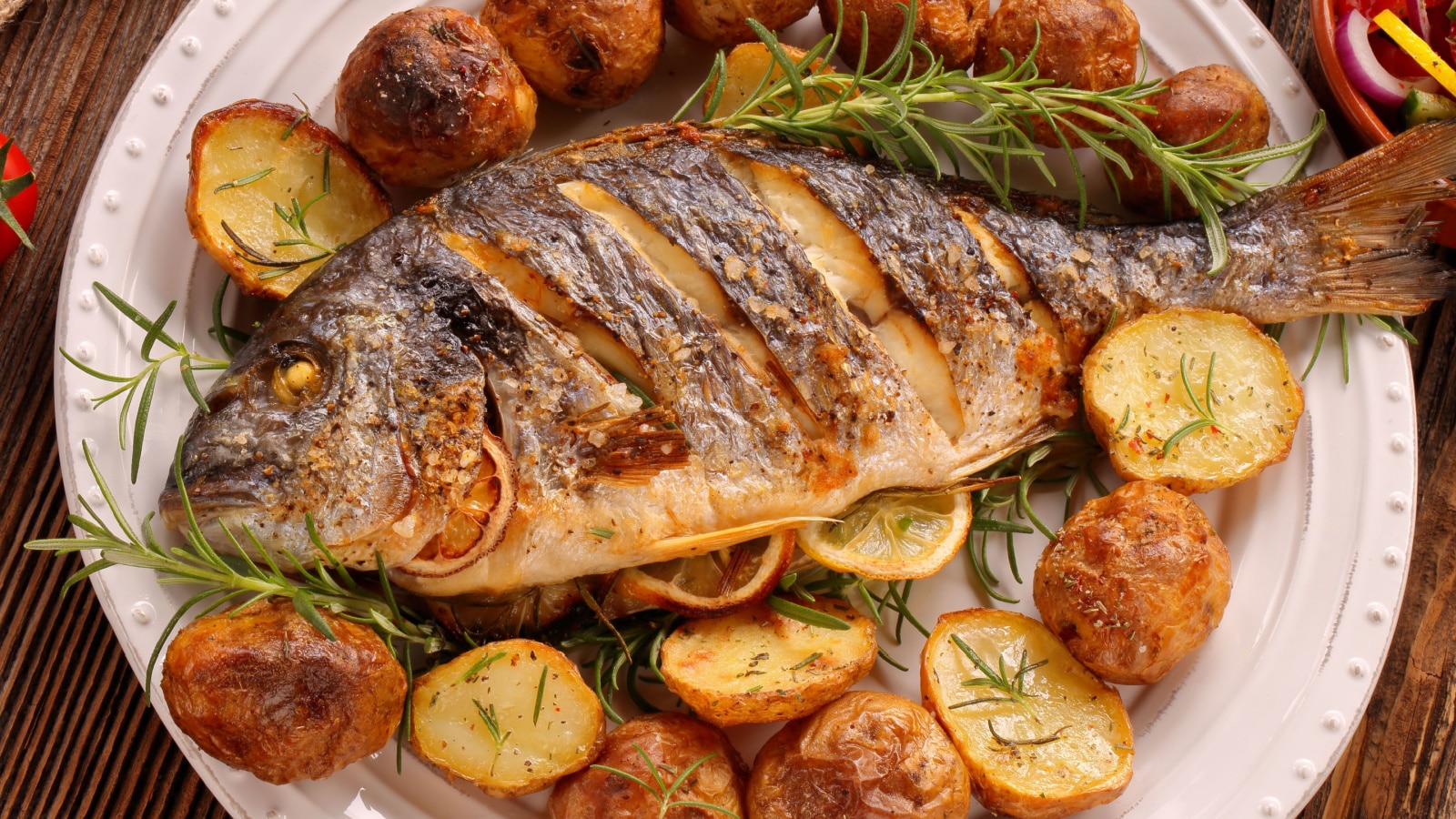 Grilled fish with roasted potatoes and vegetables on the plate