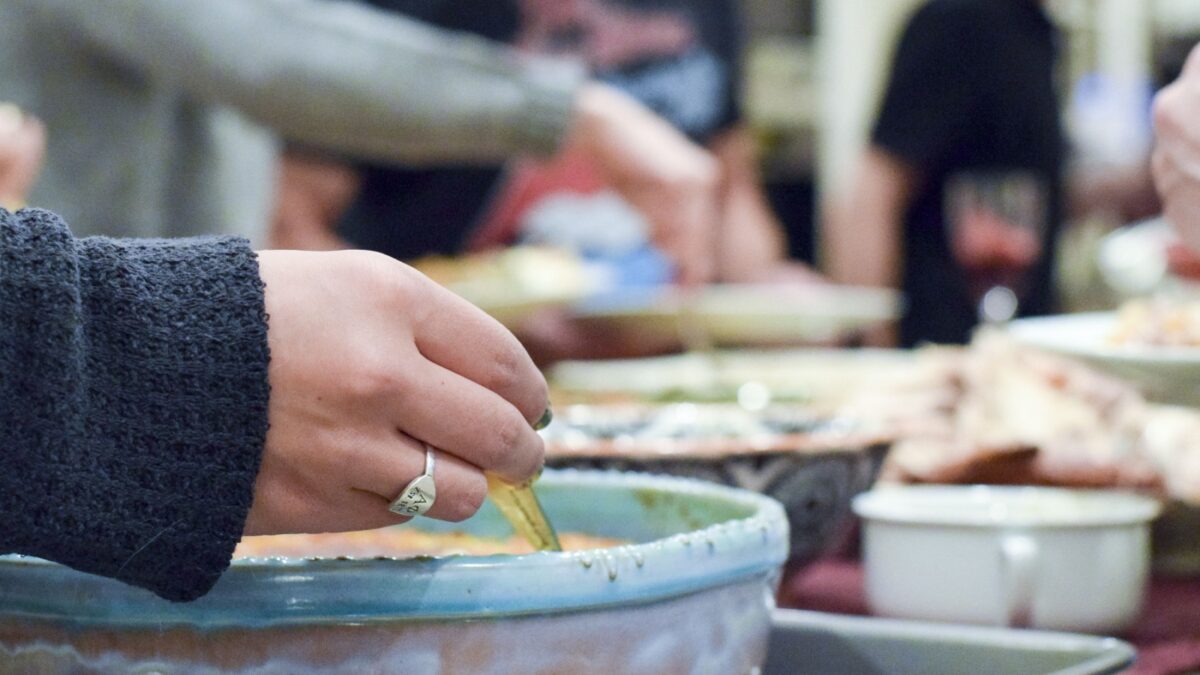 People serving themselves Thanksgiving dinner from various different casseroles and pans