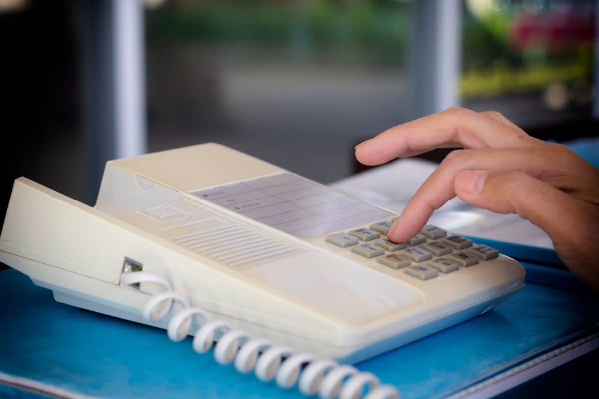 Female hand holding retro home telephone receiver and dialing number.