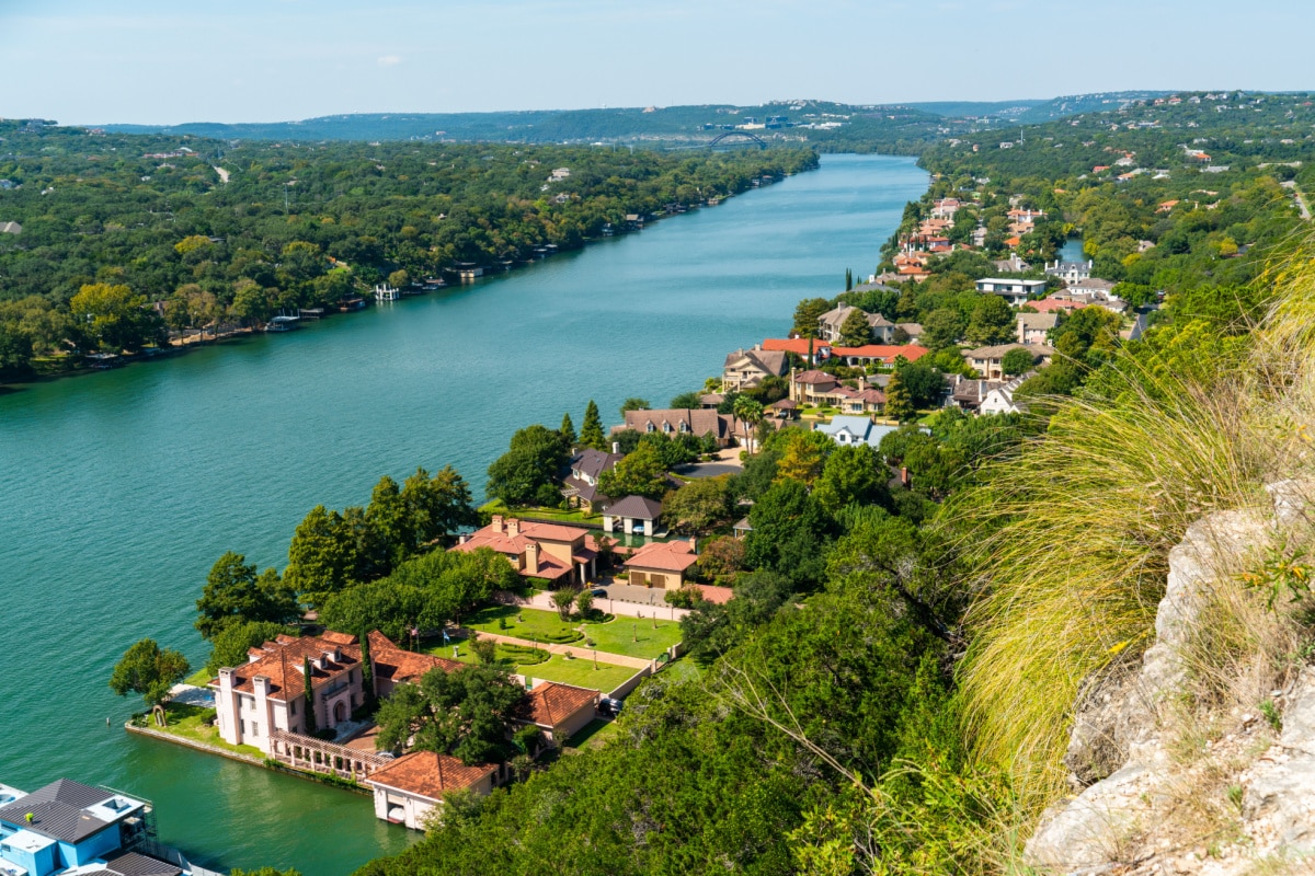 cliffside grasses growing with end of summer landscape mount Bonnell views of colorful rooftops and mansions in nature in Austin , Texas , USA