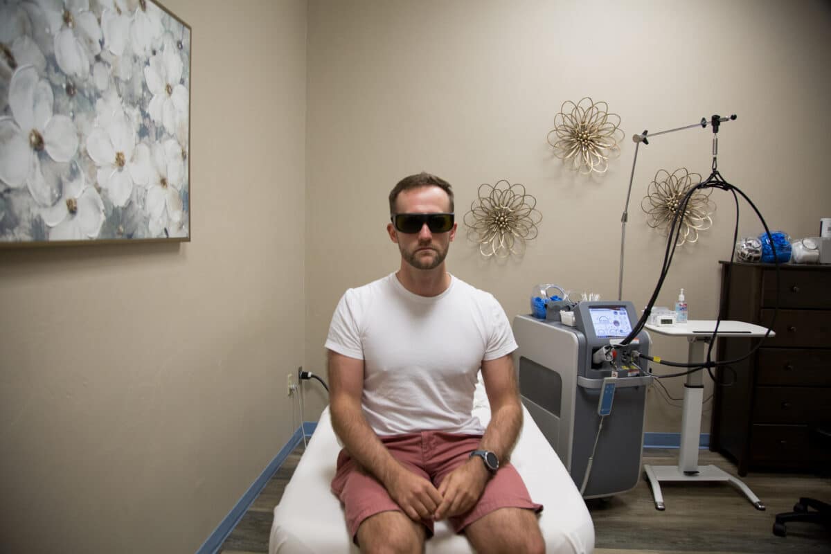 Zac sitting on the treatment bed with goggles on ready for his laser hair removal treatment.