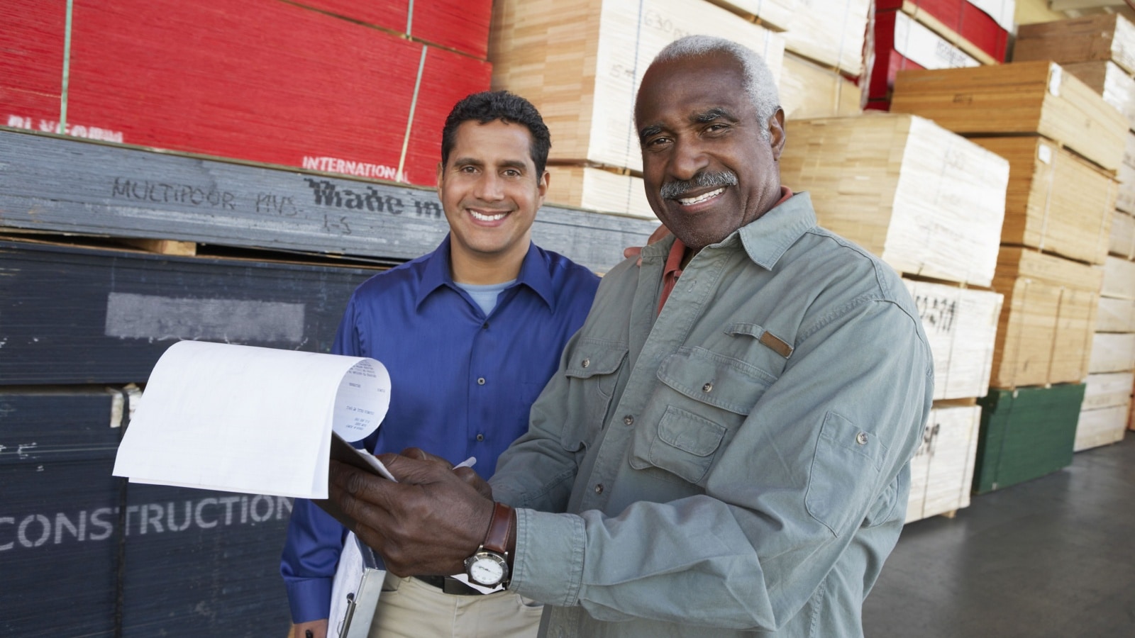 Happy warehouse workers holding clipboards