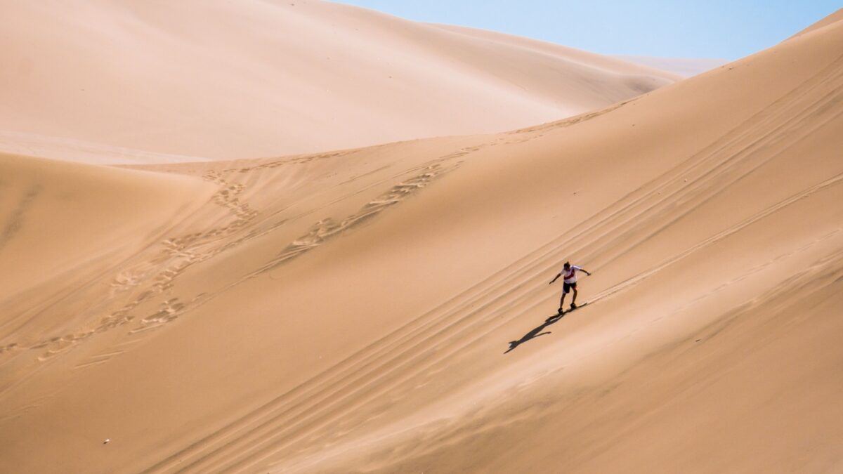 silhouette of man practice sandboarding in the desert of Peru.