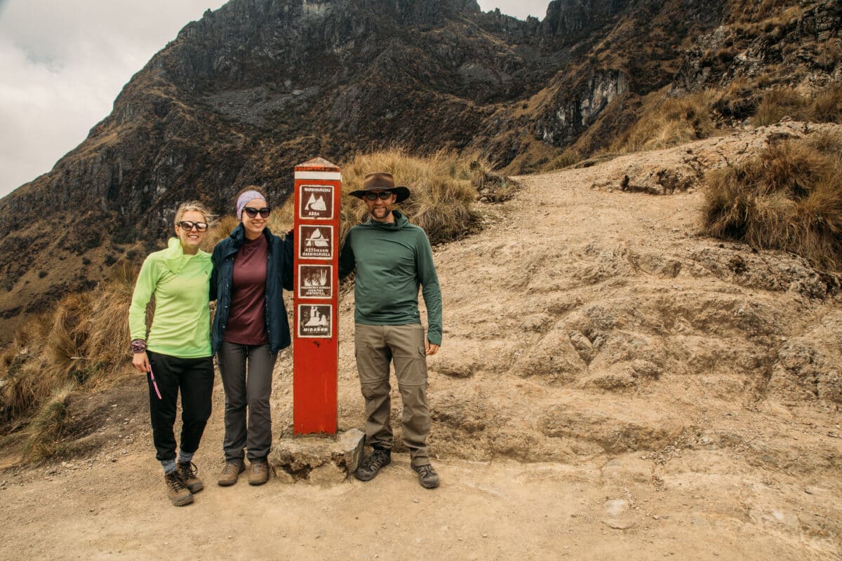 A group of hikers standing by Dead Woman's Pass sign