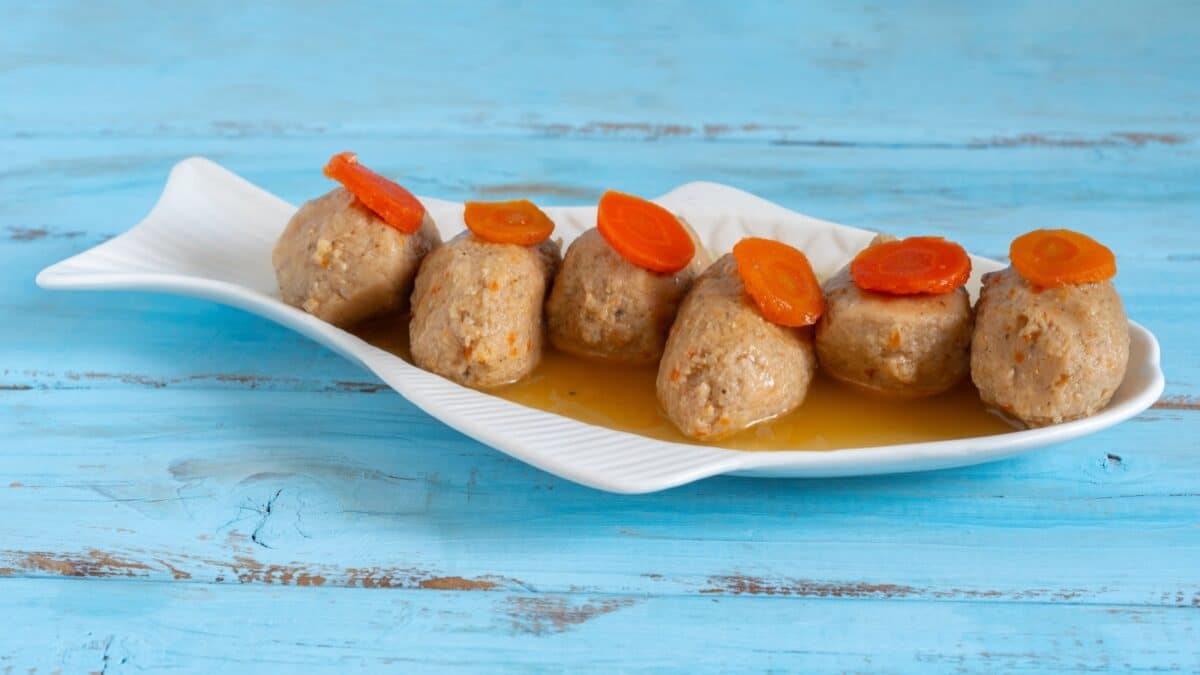 Gefilte fish served with carrot pieces on fish shaped plate for Jewish holiday Rosh Hashanah, Pesach.