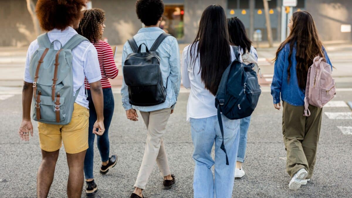 Diverse college students walking and chatting on a campus walkway during a sunny autumn day.