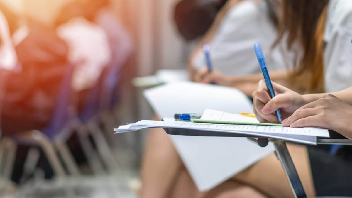 Exam at school with student's taking educational admission test in class, thinking hard, writing answer in university classroom, education and world literacy day concept