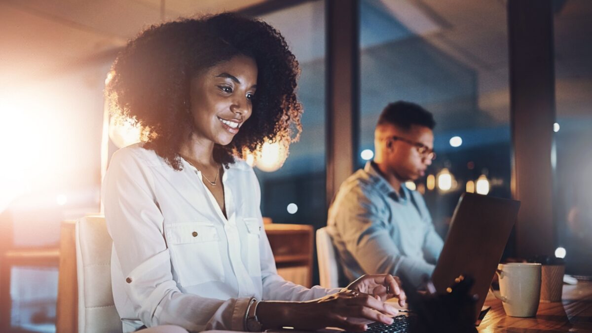 Laptop, night and business woman in office with research for wealth management report with deadline. Computer, typing and African female actuary working overtime on financial investment analysis.