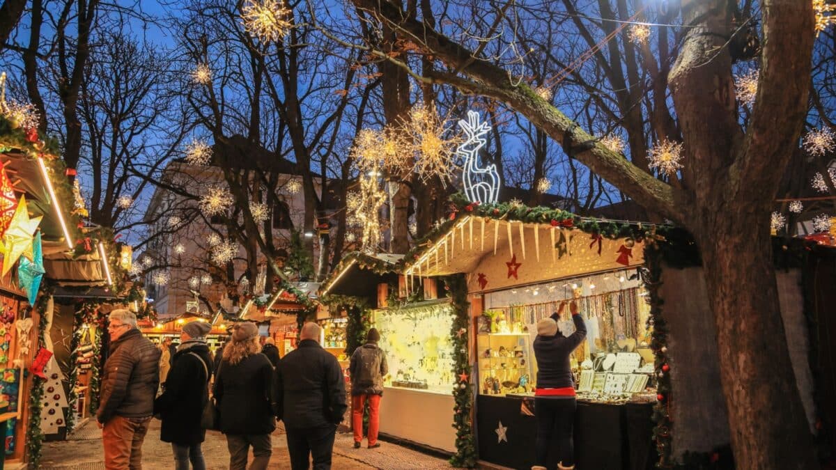 Basel, Switzerland - December 05. 2022: Traditional Christmas market in the evening on the Muenster square with beautiful illumination lights and street booths and visitors