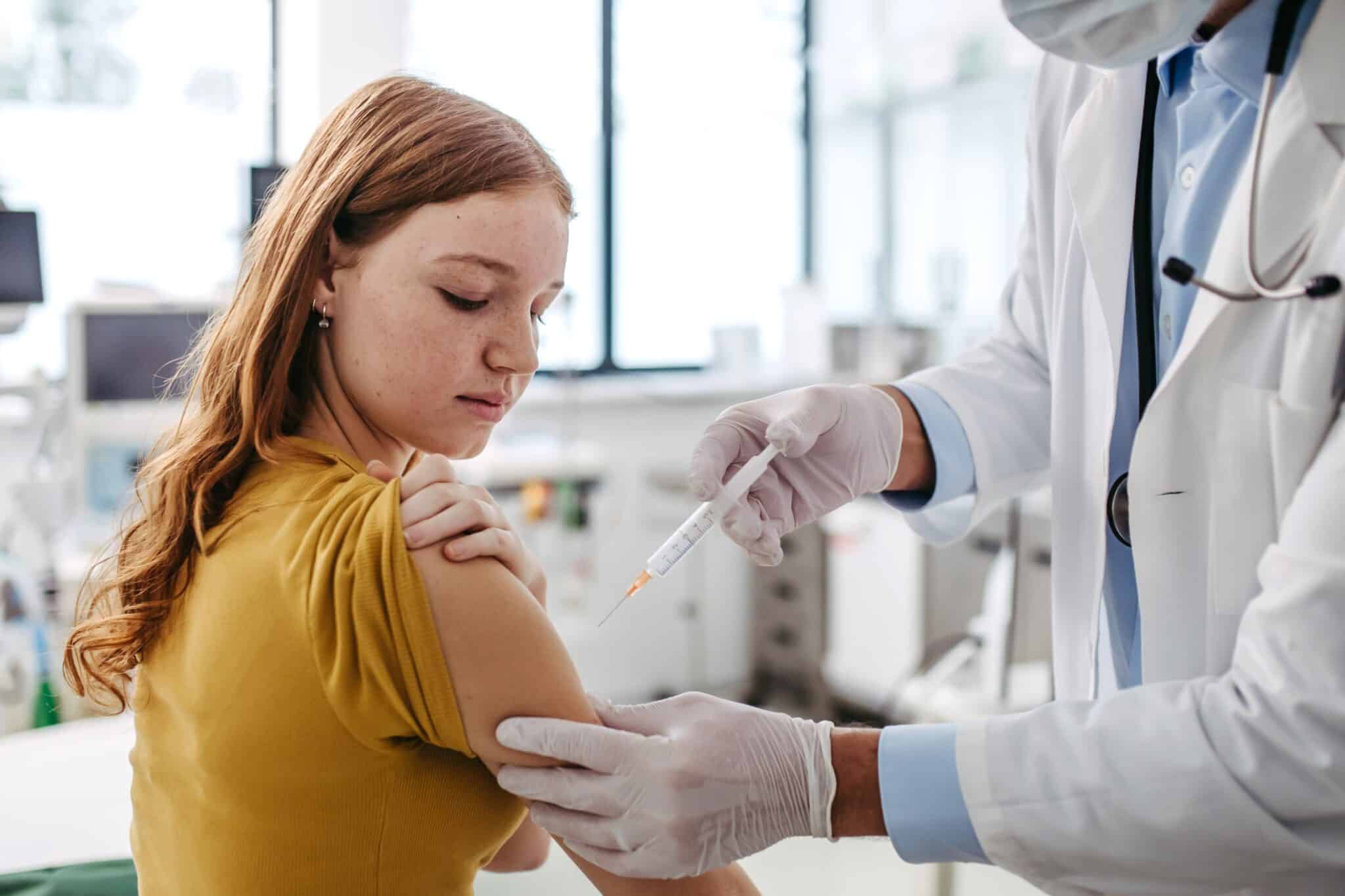 Doctor, pediatrician injecting vaccine into teenage girl arm. Concept of preventive health care and vaccination for teenagers.